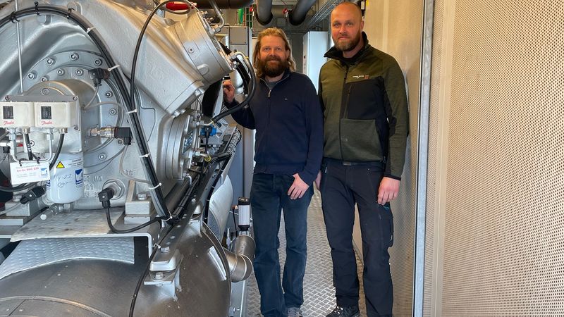 With a heat pump connected to DTU's data center, engineers Esben Højrup and Bjarke Nonbøl from DTU Campus Service utilize waste heat from the cooling servers. The heat pump supplies heat to the district heating network on Risø Campus.