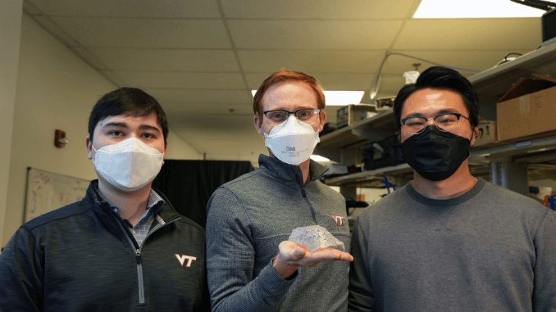 The researchers holding a piece of material that has been warped [Image Source: Virgnia Tech Blog]